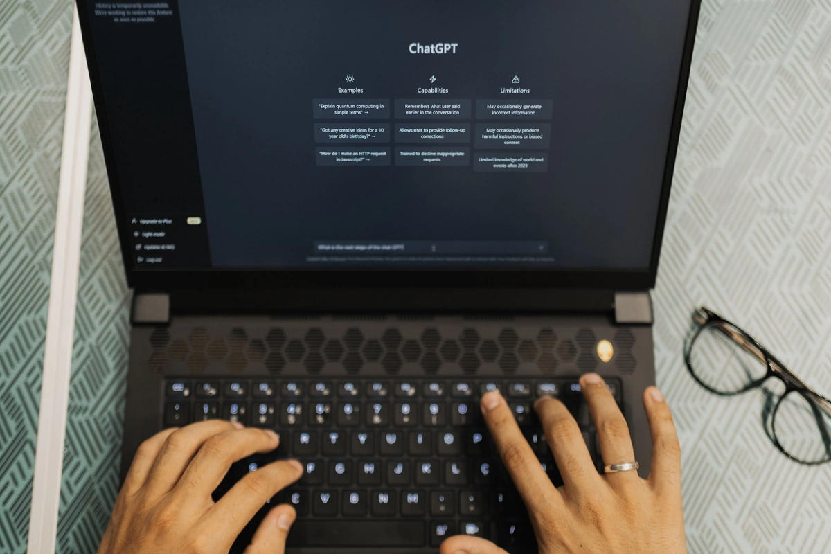 Hands typing on a laptop with an AI chat interface open on screen