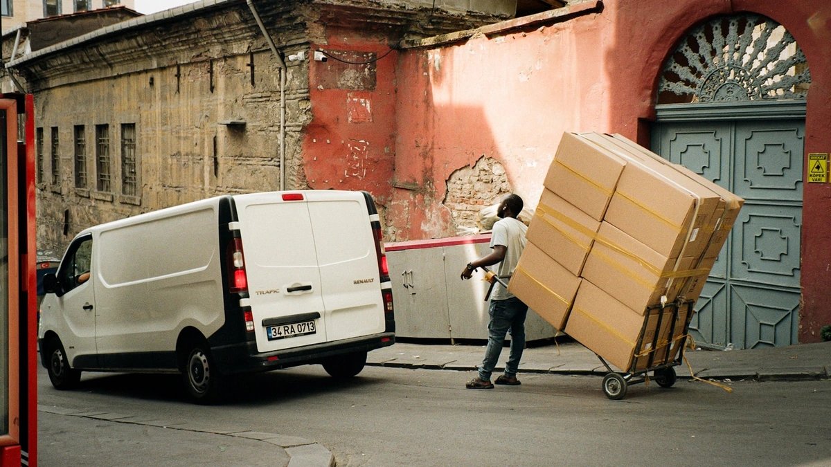 A man unloading cardboard boxes from the back of a moving van